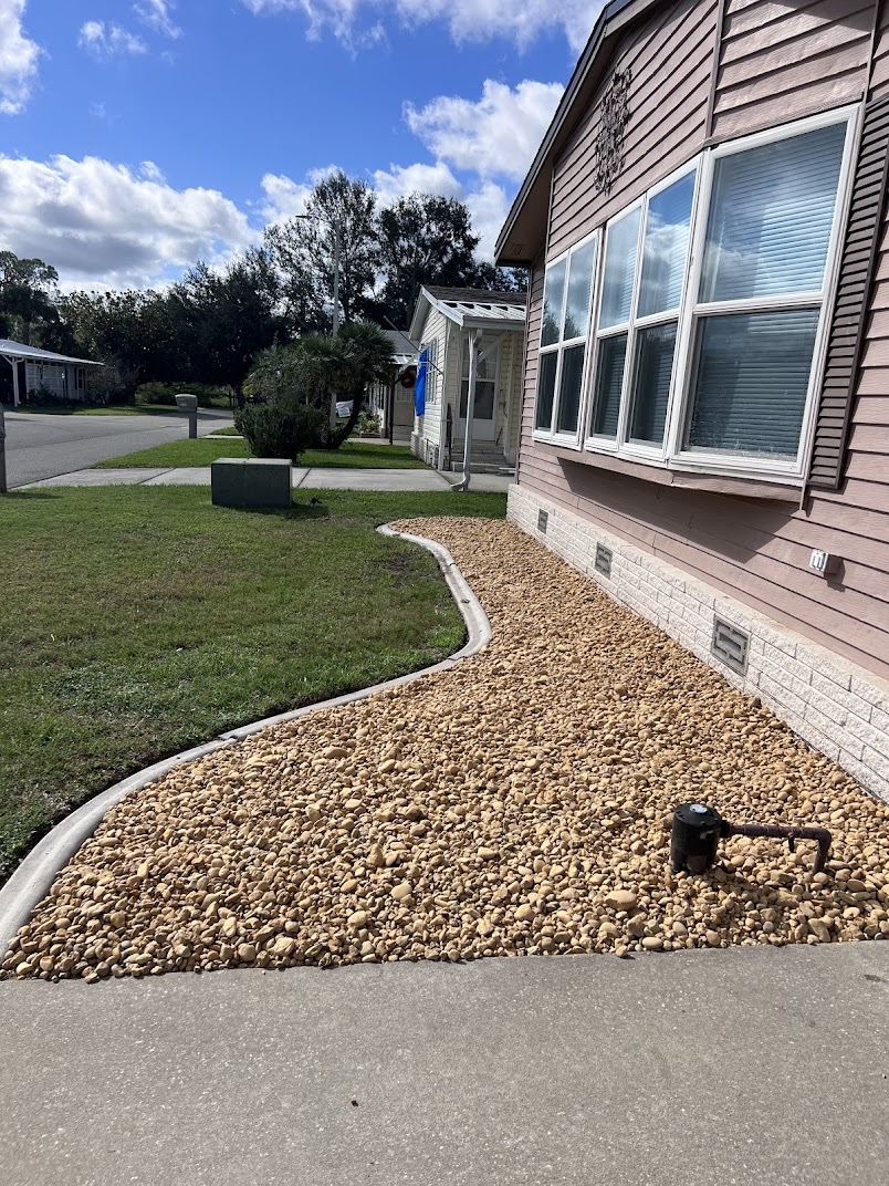 River rock bed installation along a Florida home foundation